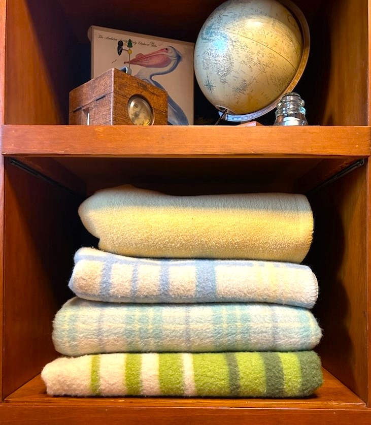 Collected wool blankets neatly stacked on shelf from travels